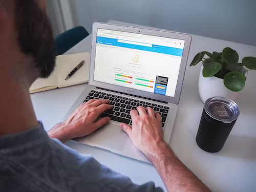 Small business owner utilising SEO services on laptop with coffee on desk.