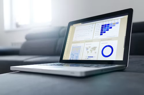 Laptop displaying online marketing strategies for small businesses graphs on a couch.