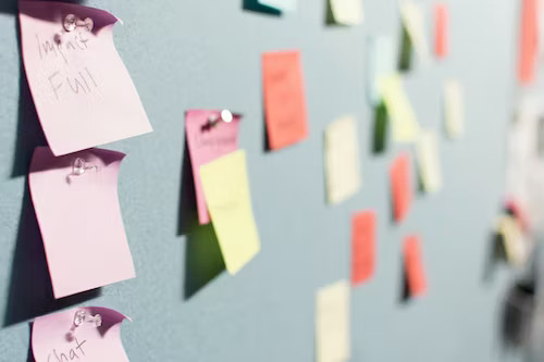 Marketing plan ideas for small business on sticky notes in office setting.